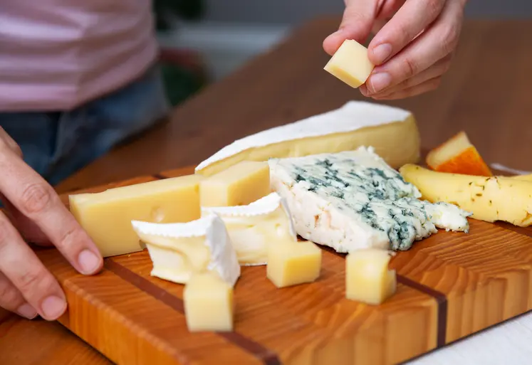 Une femme prend un bout de fromage d'un plateau.