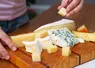 Une femme prend un bout de fromage d'un plateau.