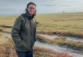 Une éleveuse se tient devant le Mont-Saint-Michel
