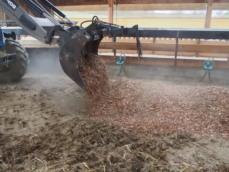 <em class="placeholder">Des plaquettes sont épandues à l'aide d'un tracteur dans une bergerie.</em>