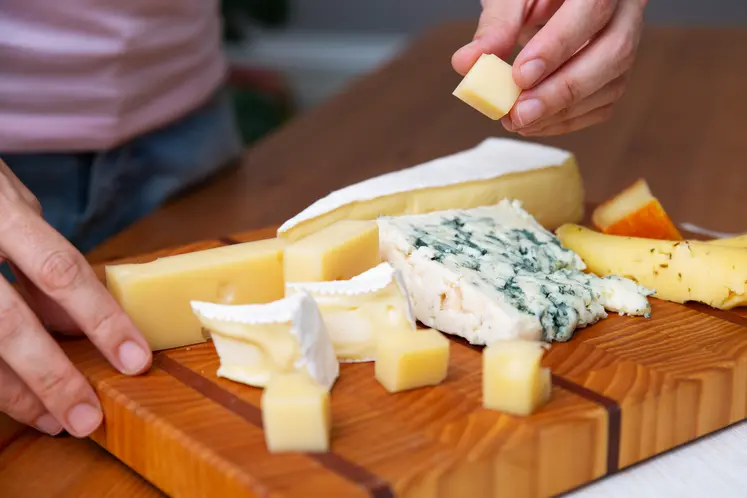 Une femme prend un bout de fromage d'un plateau.