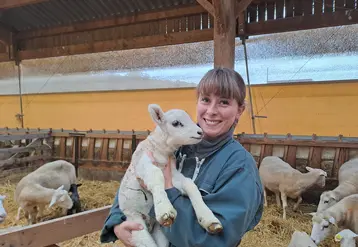 Une éleveuse tient dans ses bras un agneau.