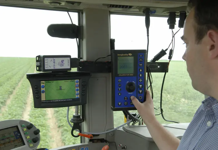 Agriculteur au volant de son tracteur devant le tableau de commande du pulvérisateur. 