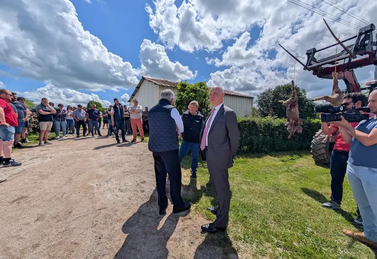 Le préfet de Saône-et-Loire discutant avec une éleveuse devant deux carcasses de moutons suspendues à un tracteur.