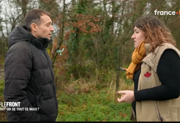 Hugo Clément discuant avec une éleveuse dans une prairie devant une haie.