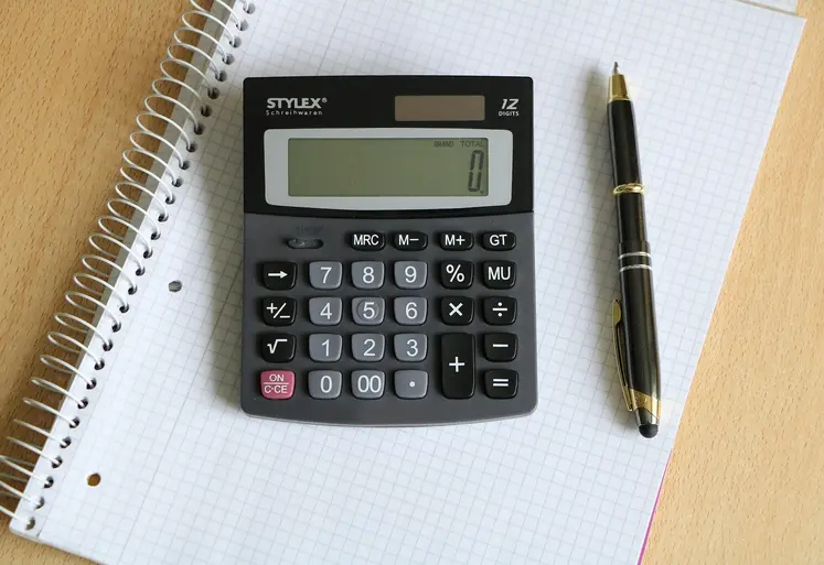 Calculatrice et bloc note avec stylo vu du haut sur un bureau. 