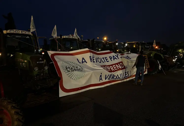 Des tracteurs et agriculteurs avec une banderole sur laquelle est écrit « la révolte paysanne reprend à Versailles »
