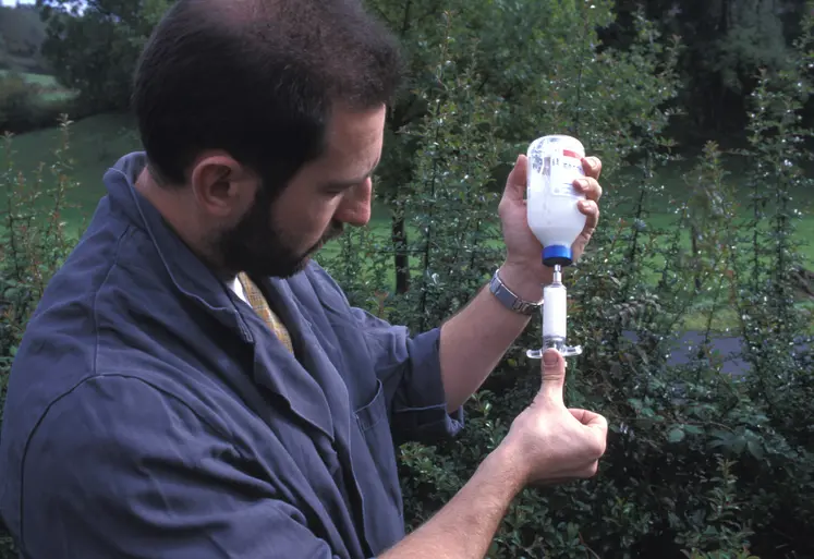 Vétérinaire réalisant un prélèvement dans un flacon d'antibiotique sur une exploitation bovine.