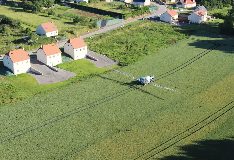 vue aérienne de maisons bordant des champs traités pas un tracteur 