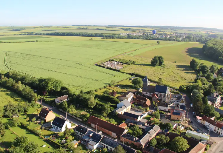 Photographie aérienne d'un paysage rural avec une exploitation agricole, un village et des champs 