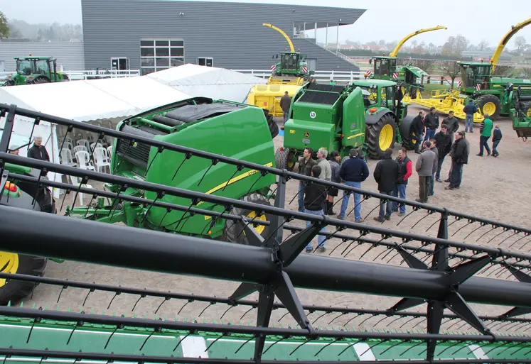 Visiteurs dans un concessionnaire John Deere devant des machines agricoles. 