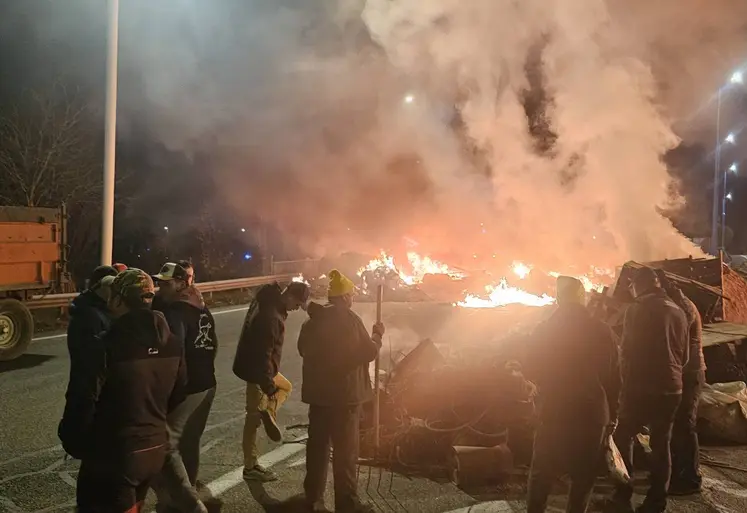 Blocage d'une voie d'autoroute le soir par des agriculteurs de la Coordination rurale, avec des pneus enflammés, des palettes de bois et des ballots de paille. 
