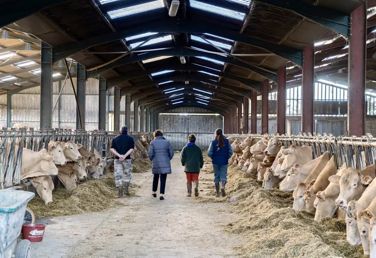 Annie Genevard de dos avec des éleveurs dans une stabulation 