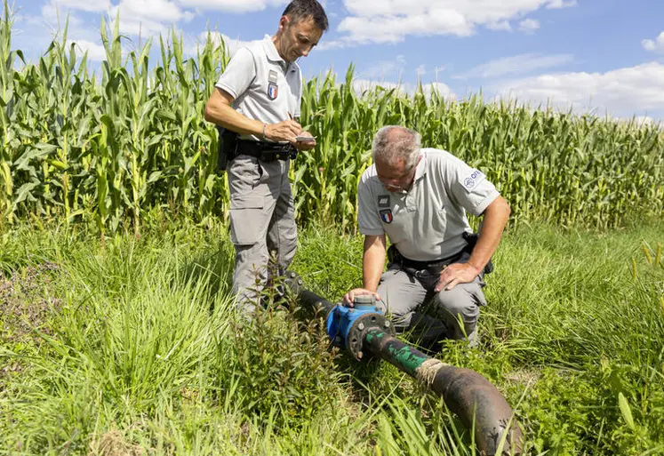 deux agents de l'OFB contrôlant un système d'irrigation devant un cham de maïs
