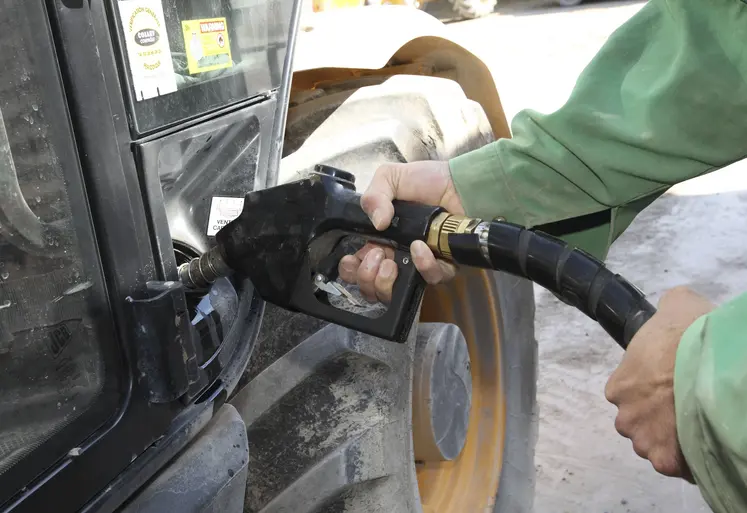 agriculteur tenant un pistolet pour faire le plein de son tracteur