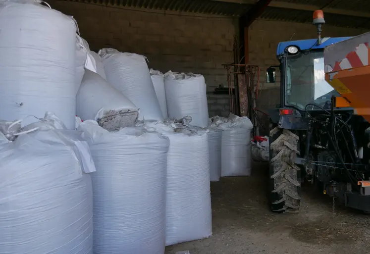 des sacs d'engrais et un tracteur entreposés dans un hangar agricole