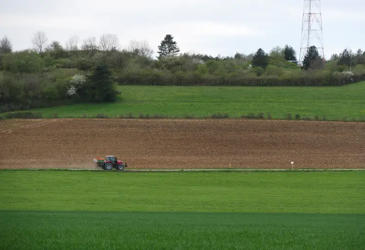 Paysage de grandes cultures en Bourgogne avec un tracteur visible dans un champ. 