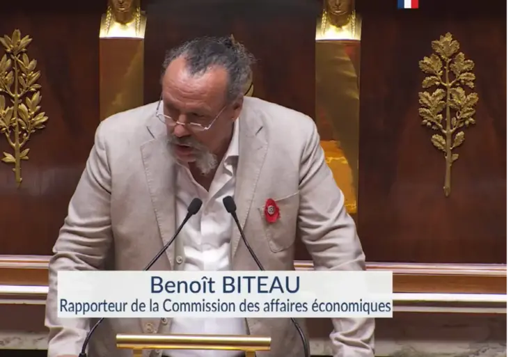 un homme à la tribune de l'assemblée nationale s'exprimant devant un micro