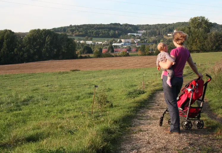   Femme avec son bébé dans les bras en promenade dans les champs  