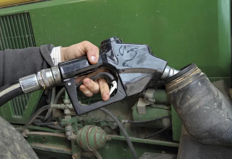  Main sur un pistolet de carburant au-dessus du réservoir d’un tracteur.
