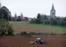 Tracteur semant du  blé à l'autome devant un village.