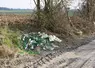 Déchets près d'un terrain agricole. On voit des bouteille en verre. 