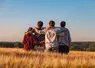 Quatre jeunes de dos se tenant par les épaules au milieu d'un champ.