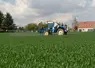 au premier plan un tracteur utilisant des pesticides et en arrière plan une maison