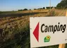 panneau avec la mention "camping" devant un champ
