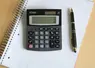 Calculatrice et bloc note avec stylo vu du haut sur un bureau. 