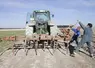Deux agriculteurs mettant en place une herse de 4 mètres pour préparer les bords de champs    