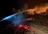 Lance à eau ciblant les flammes et les braises en soirée lors de l'incendie historique ayant touché l'Aude depuis le 5 août.