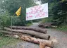Route bloquée par des troncs d’arbre avec un pancarte « stop aux massacres des vaches » et un drapeau de la Coordination rurale