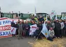 Des agriculteurs sur une botte de paille avec banderole "la révolte paysanne reprend à Versailles" devant le château de Versailles.