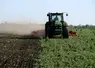 Un agriculteur dans son tracteur détruit un couvert végétal de légumineuses.