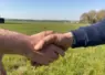 gros plan sur unepoignée de mains entre deux hommes dans un champ