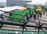 Visiteurs dans un concessionnaire John Deere devant des machines agricoles. 