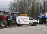 Tracteurs bloquant une route, avec une banderole sur une voiture "Mercosur ouvert, nos fermes en enfer"