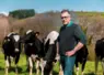 Un homme posant devant ses vaches en extérieur