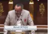 un homme à la tribune de l'assemblée nationale s'exprimant devant un micro