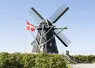 drapeau planté dans un champ devant un moulin