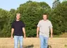 deux hommes posent pour la photo dans un  champ