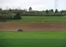 Paysage de zone intermédiaire au printemps, avec un tracteur dans un champ.