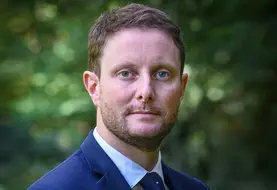Clément Beaune, Haut-Commissaire à la stratégie et au plan, en gros plan devant un fond de verdure.