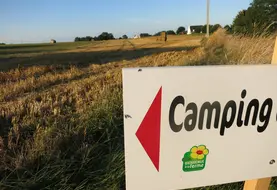 panneau avec la mention "camping" devant un champ