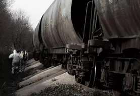 Militants en combinaison blanche à côté d'un train de marchandises dont une partie de la cargaison de blé a été deversée sur les rails.
