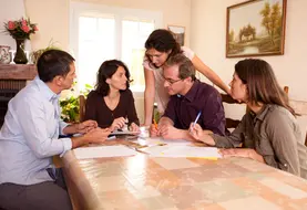 Adhérents MSA assis à table réalisant des tâches administratives sur des feuilles papier. 