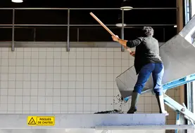Travail en cave d’un salarié après livraison du raisin pour vinification. Un panneau de signalisation du danger de chute est visible, pour la prévention des risques d'accident. 