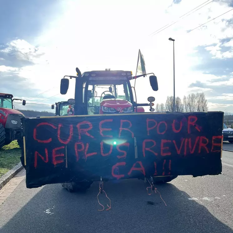 Pancarte réclamant le curages des fossés accrochée sur un tracteur