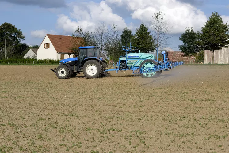 Traitement phytosanitaire dans un champ à proximité des habitations.